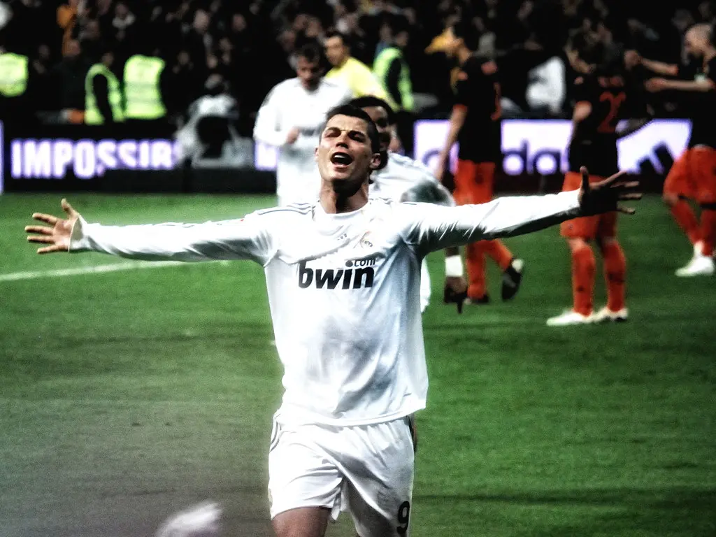 Cristiano Ronaldo com os braços abertos comemorando um gol durante uma partida de futebol.